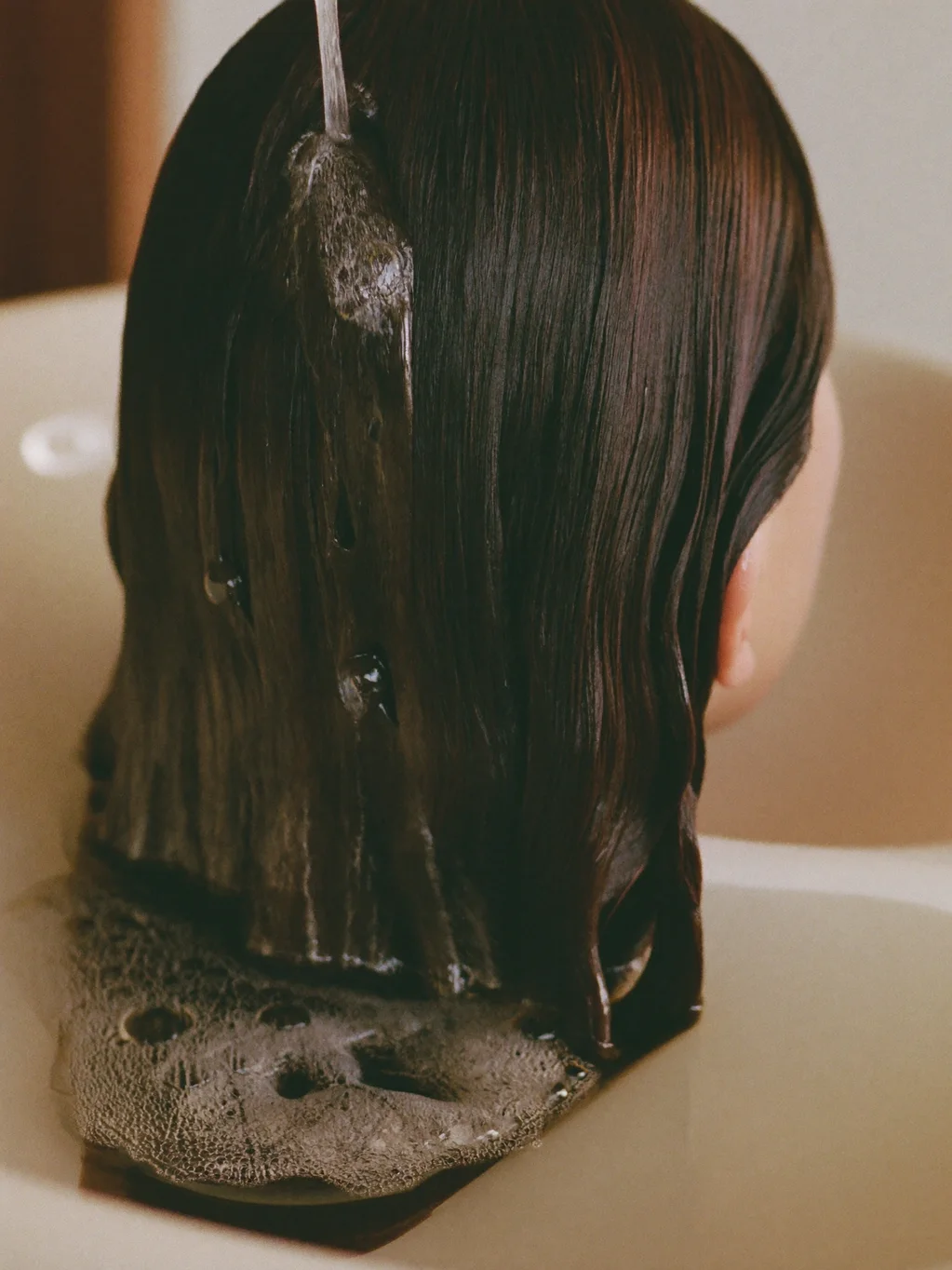 Cabello húmedo con espuma suave durante el lavado en el lavacabezas