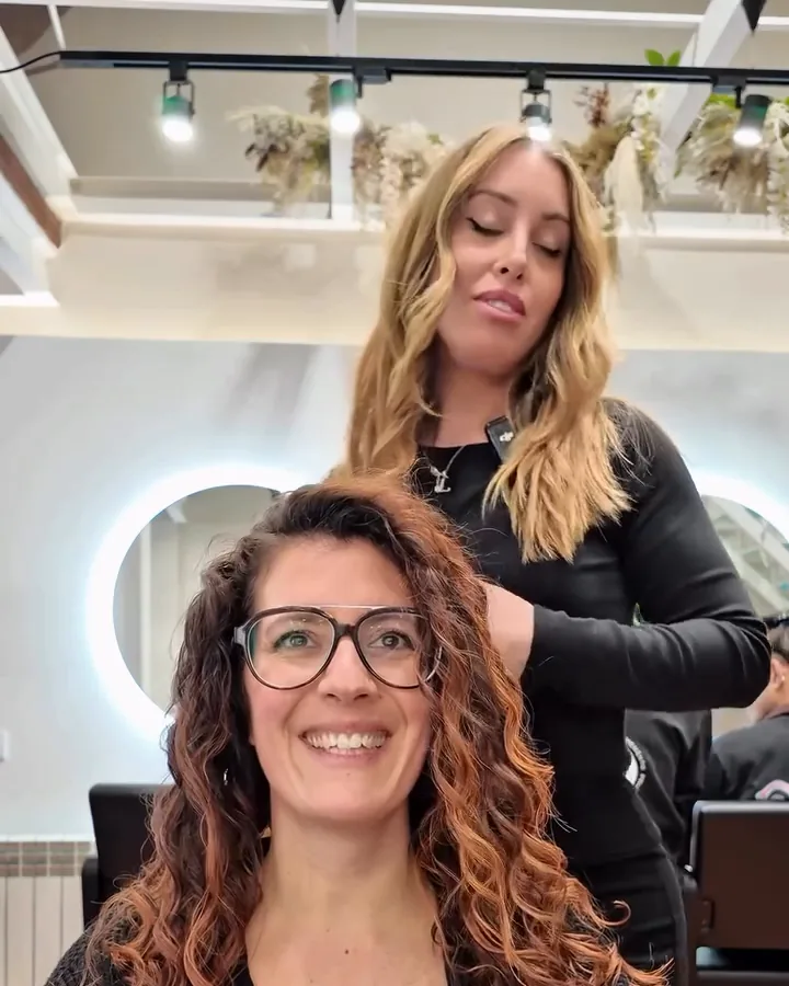 Ari smiling at the end, with defined, shiny curls, at the salon in Gràcia. Still from the salon's video.