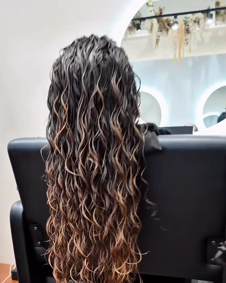 Laura's hair seen from behind, still wet, with the curls already grouped before drying. Still from the salon's video.